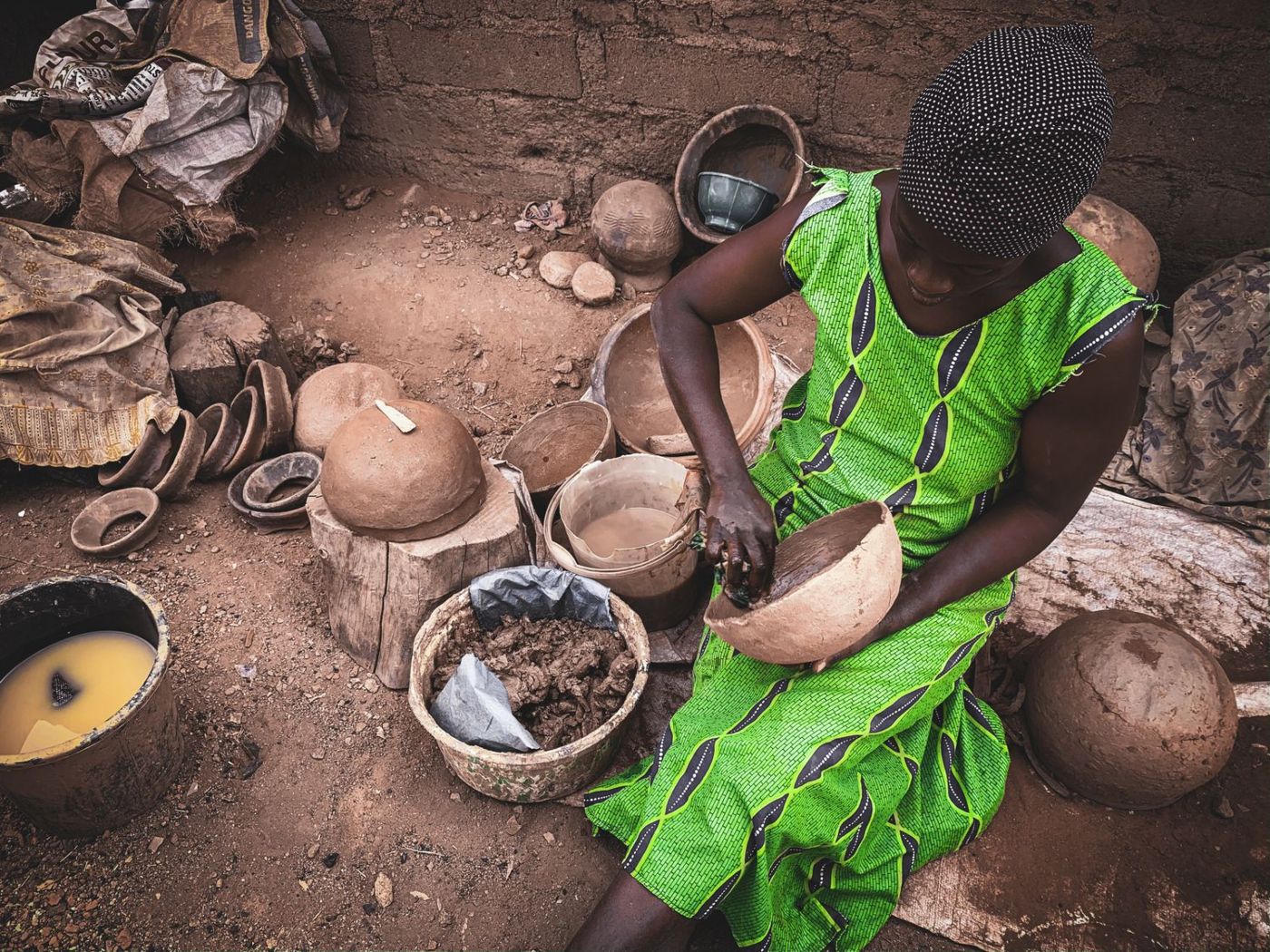 Femme façonnant des poteries de terre à même le sol