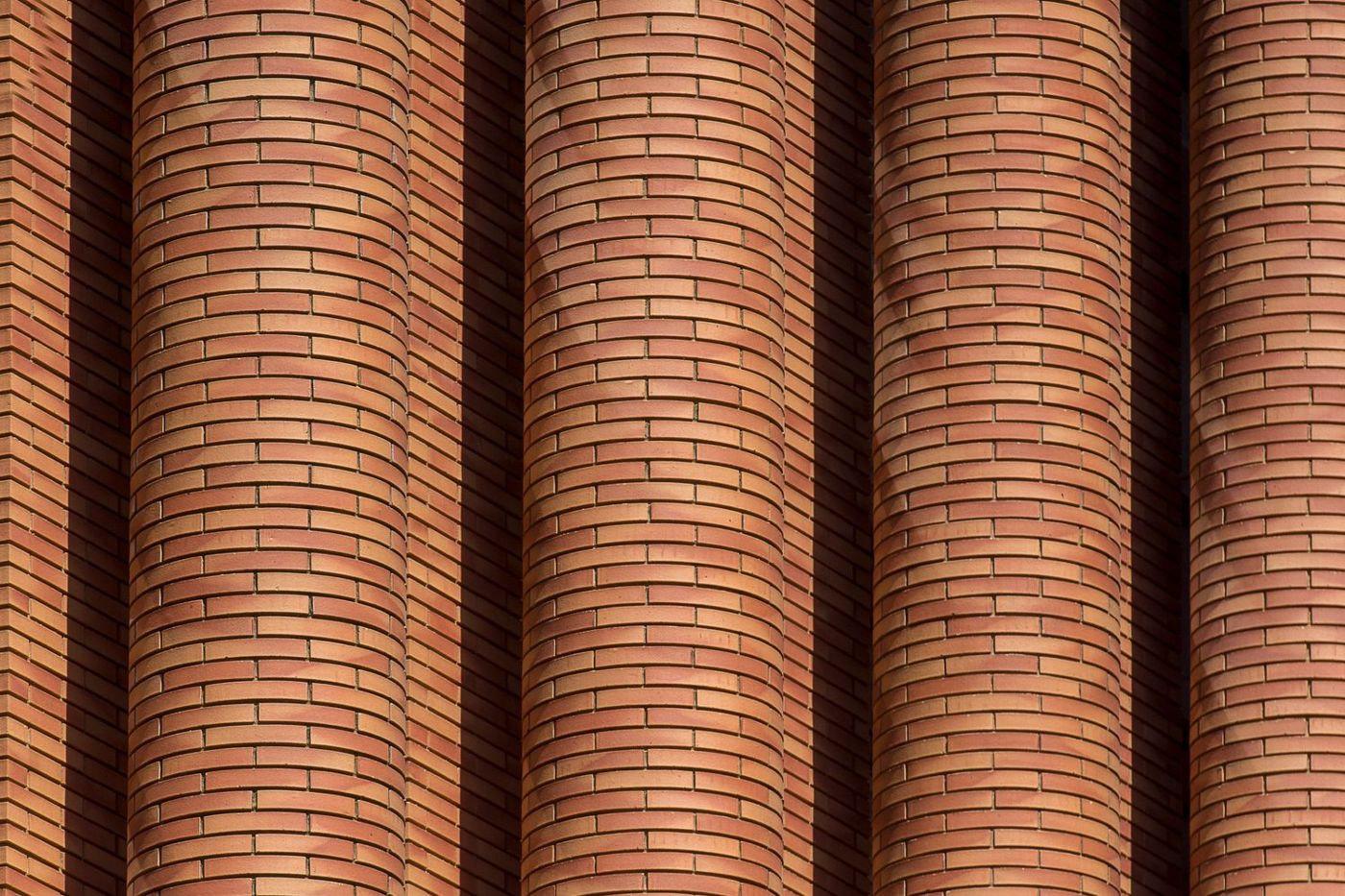 Mur en briques de parement de terre cuite, courbes lumineuses au soleil