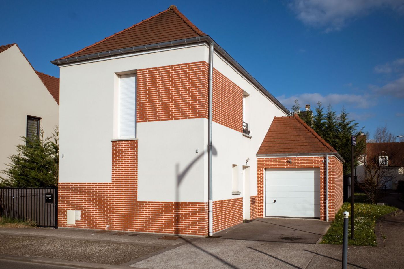 Maison dont la façade associe enduit clair et parement de terre cuite